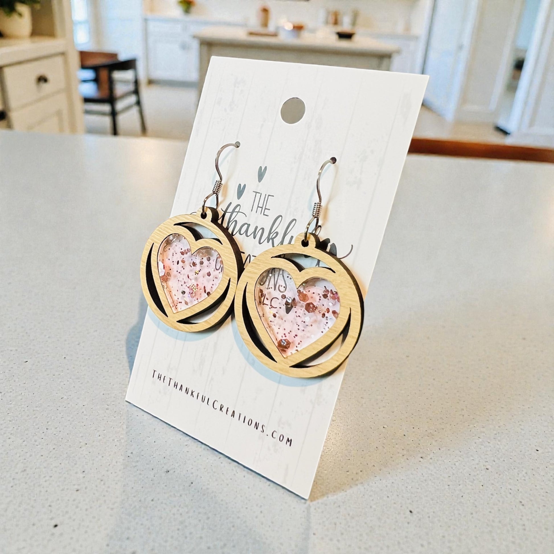Heart-shaped earrings on a branded card with a blurred indoor background