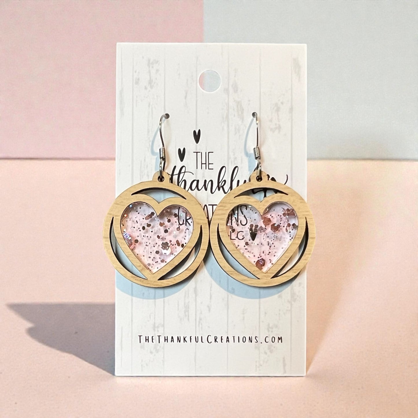 Heart-shaped earrings on a branded card with a pink and gray background