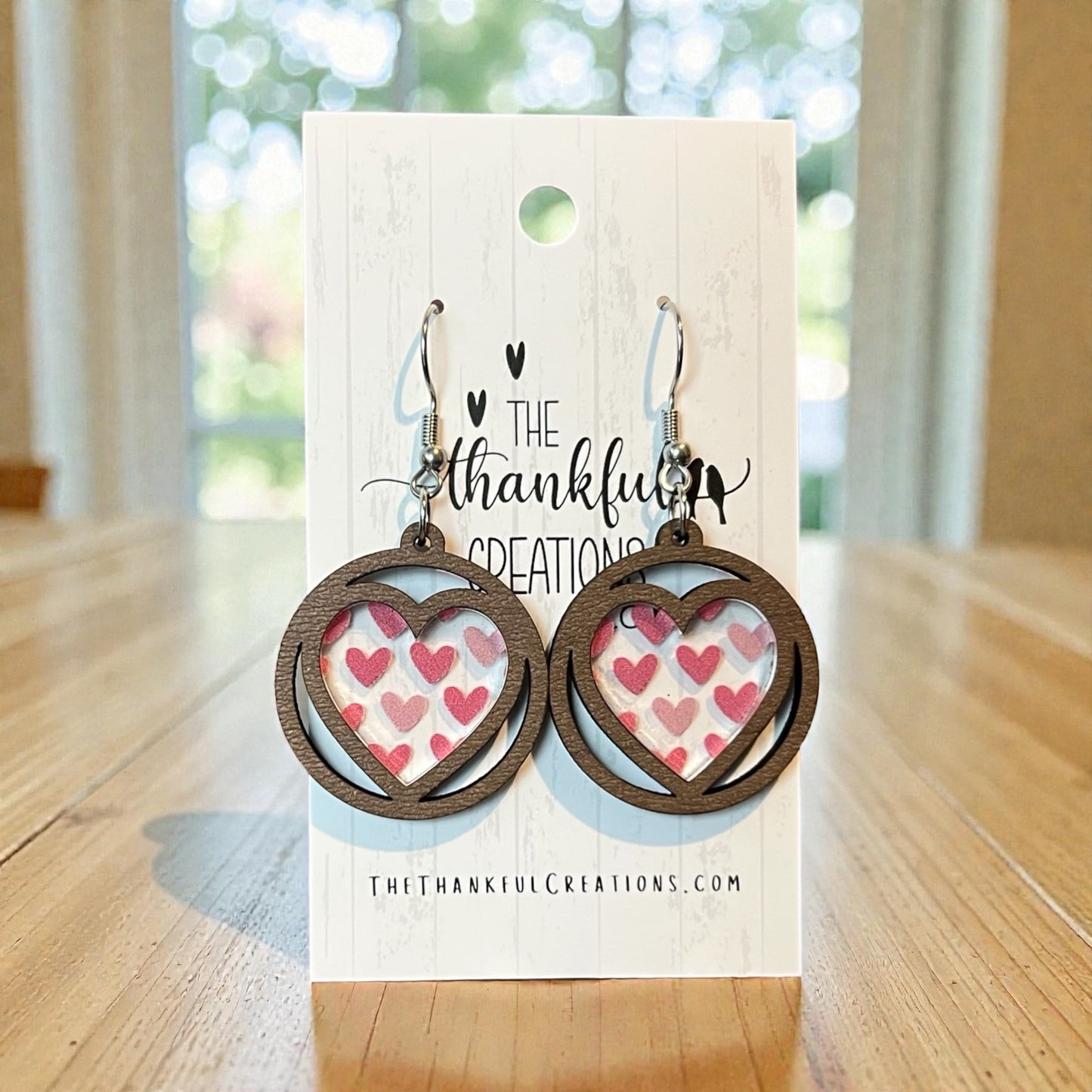 Heart-shaped earrings on a branded card with a blurred background