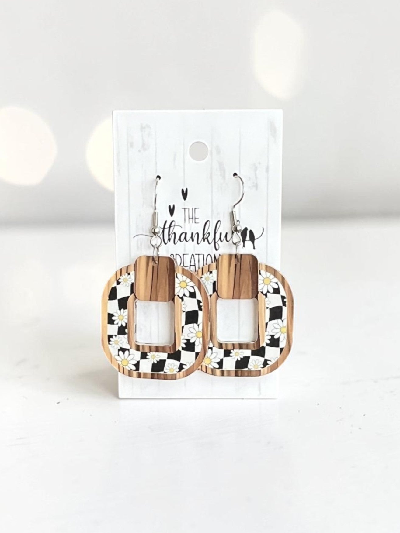 Wooden earrings with black and white checkered design on a branded card against a white background